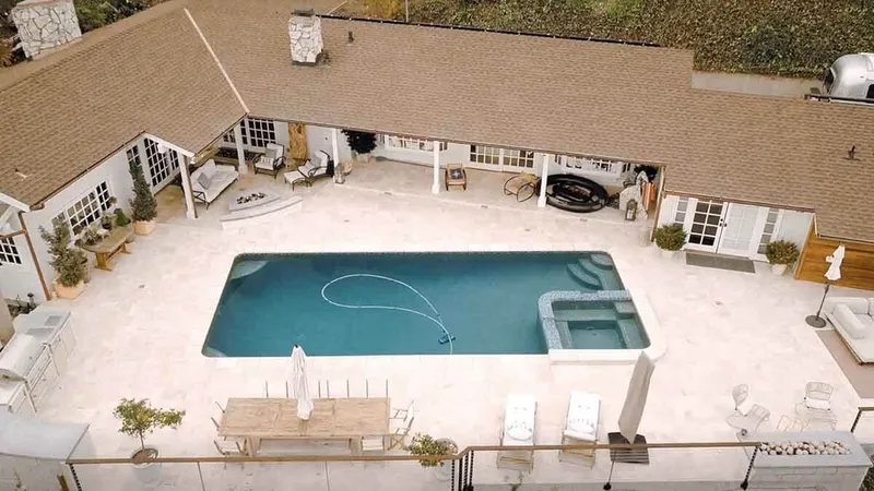Aerial view of a freeform pool with travertine decking and landscaping