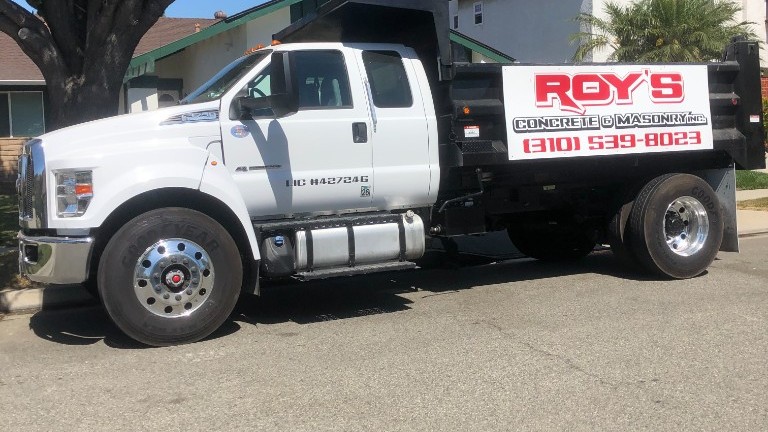 Roy's Concrete & Masonry dump truck with company logo and phone number (310) 539-8023