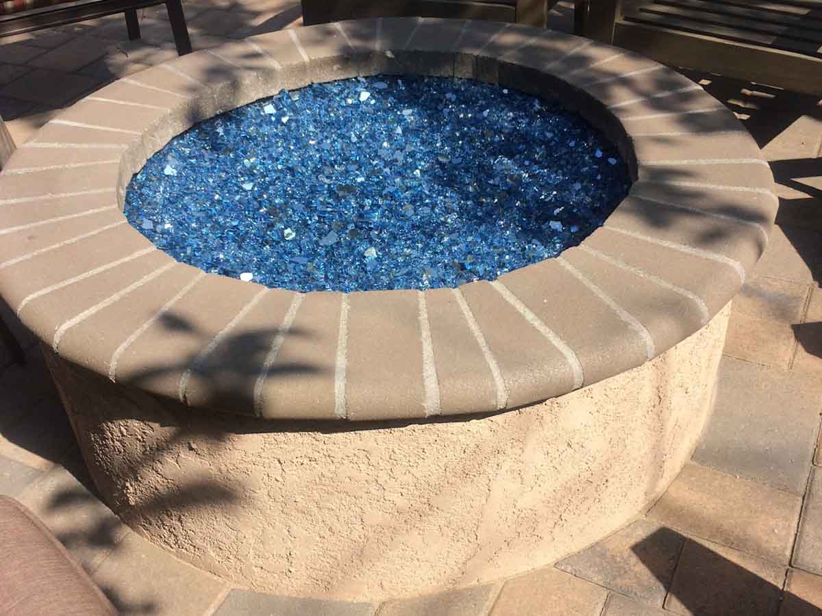 Round stucco fire pit filled with blue fire glass