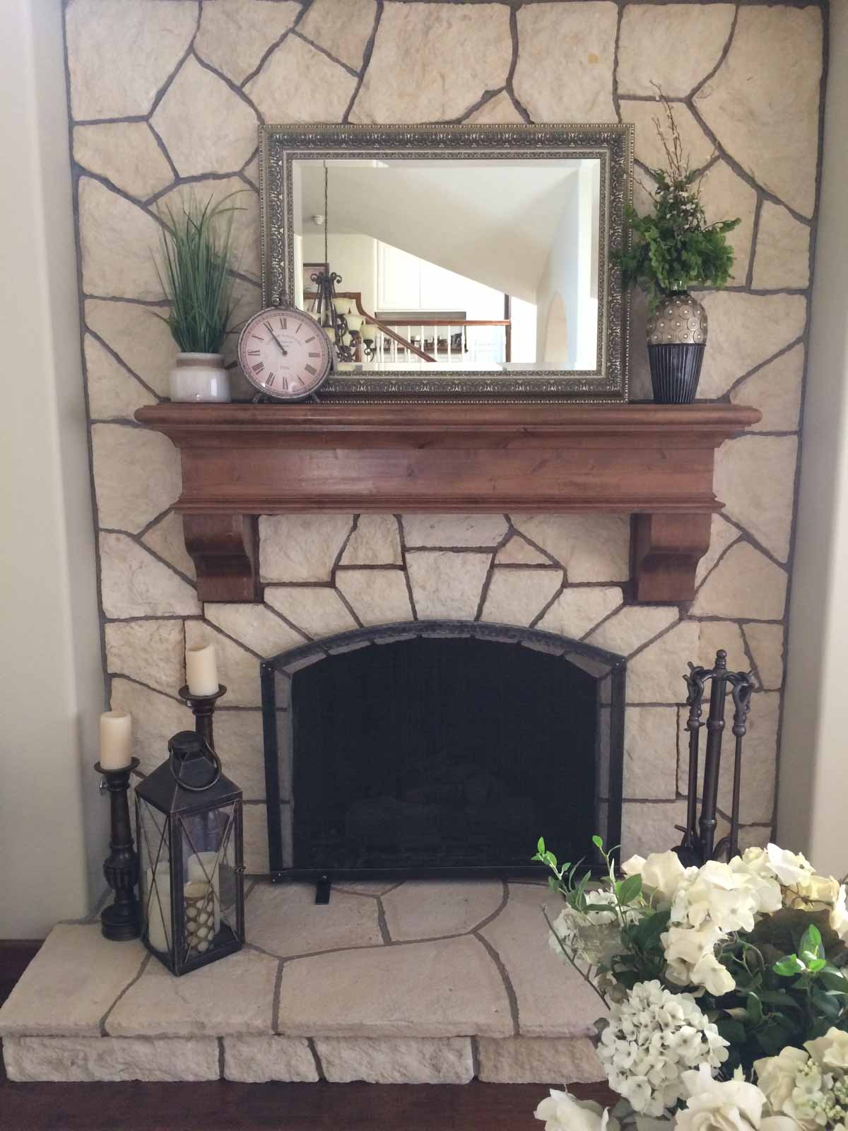 White stone fireplace surround with hearth and wood mantel