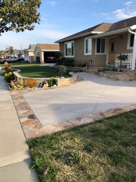 Freshly poured concrete driveway with a natural flagstone border