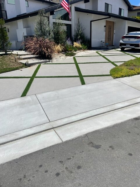 Street view of a modern driveway with large concrete panels and a turf grid