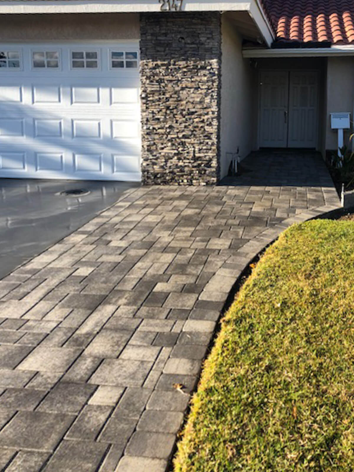 Charcoal paver driveway with a clean soldier-course edge along the lawn