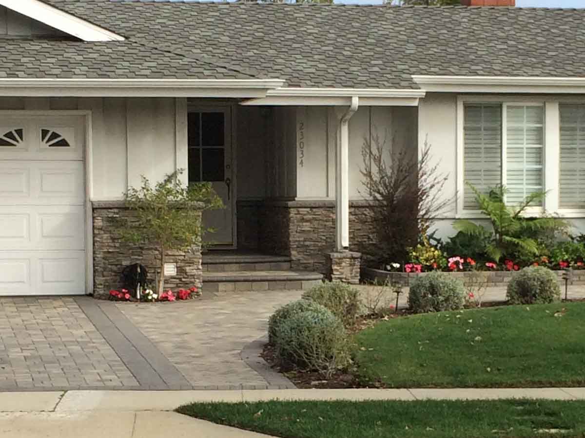 Paver driveway fronting a home with stacked stone entry columns
