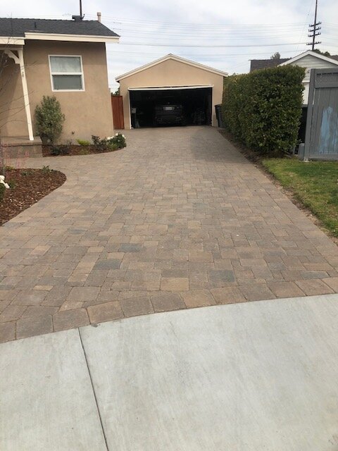 Tan paver driveway running between houses to a rear garage