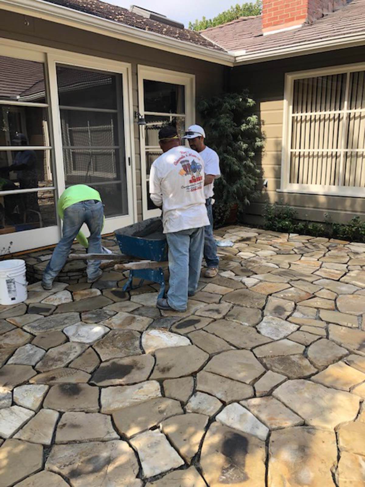 Crew member hand-fitting Lompoc stone on a patio