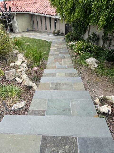 Bluestone slab steppers set through gravel and plantings along the side of a house