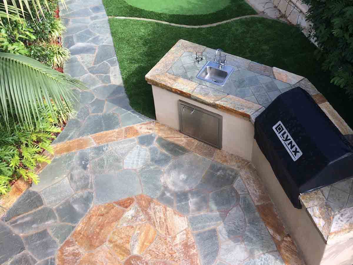 Flagstone patio and walkway wrapping a BBQ island with a built-in grill and sink