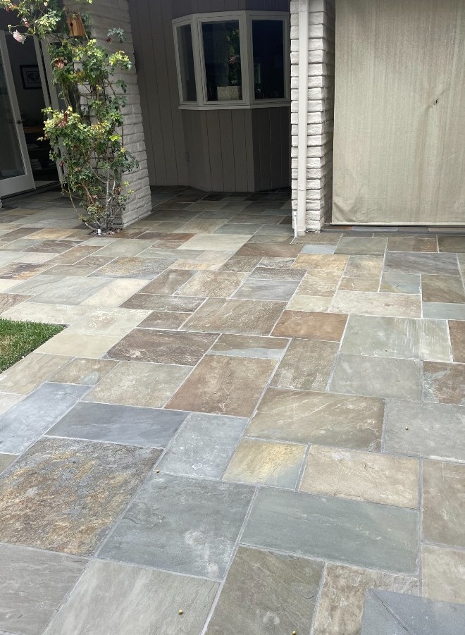 Multicolor rectangular flagstone patio beside a bay window and white brick columns