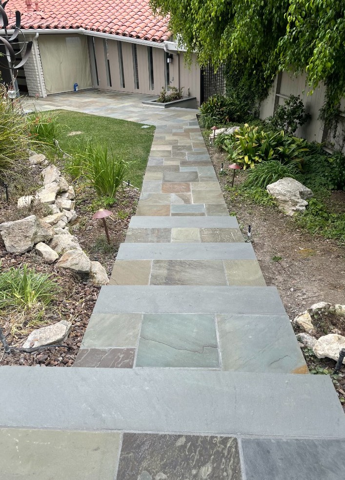 Multicolor flagstone walkway and shallow steps rising through a planted garden to a patio