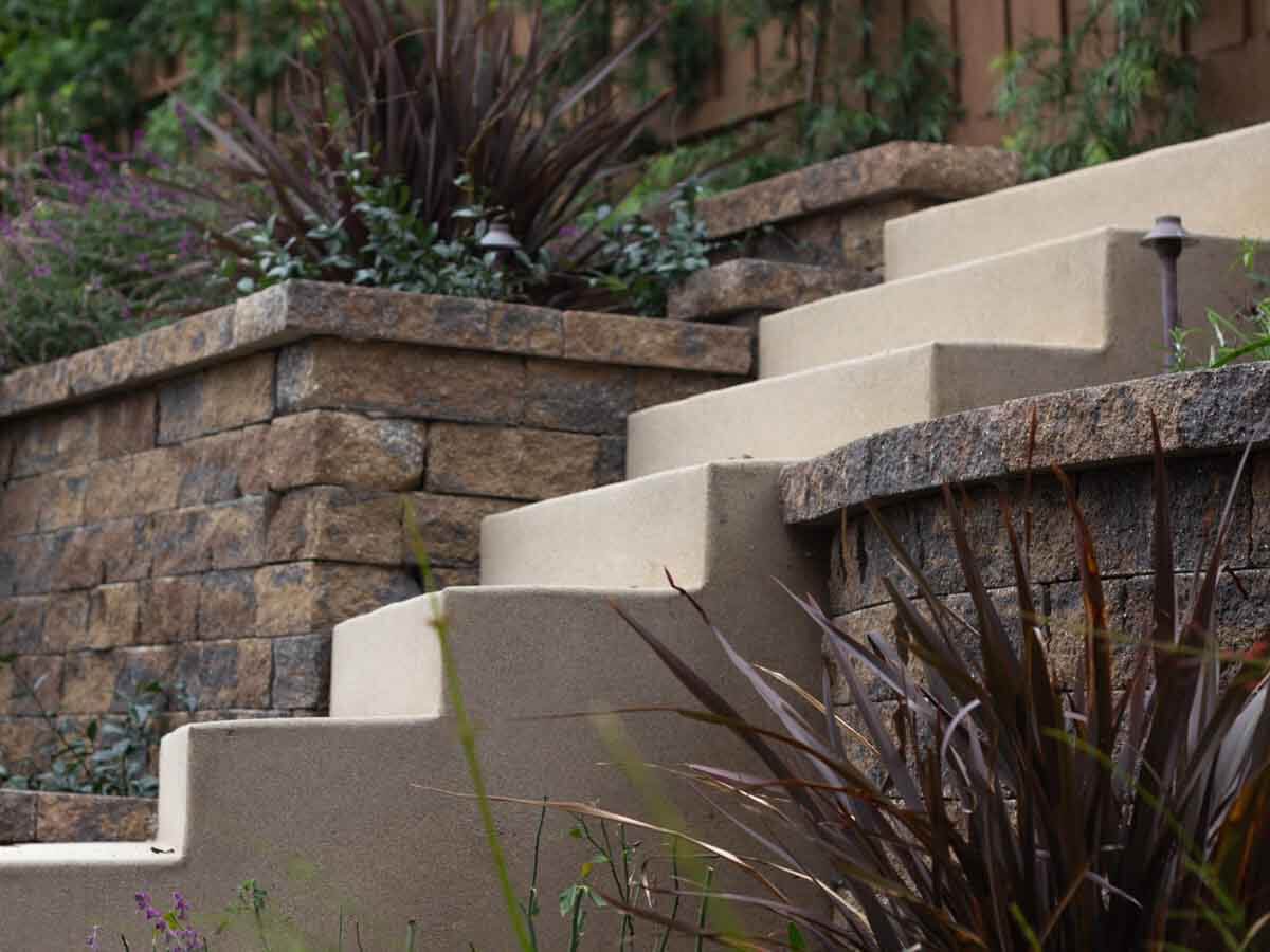 Colored concrete steps zigzagging up between split-face block garden walls