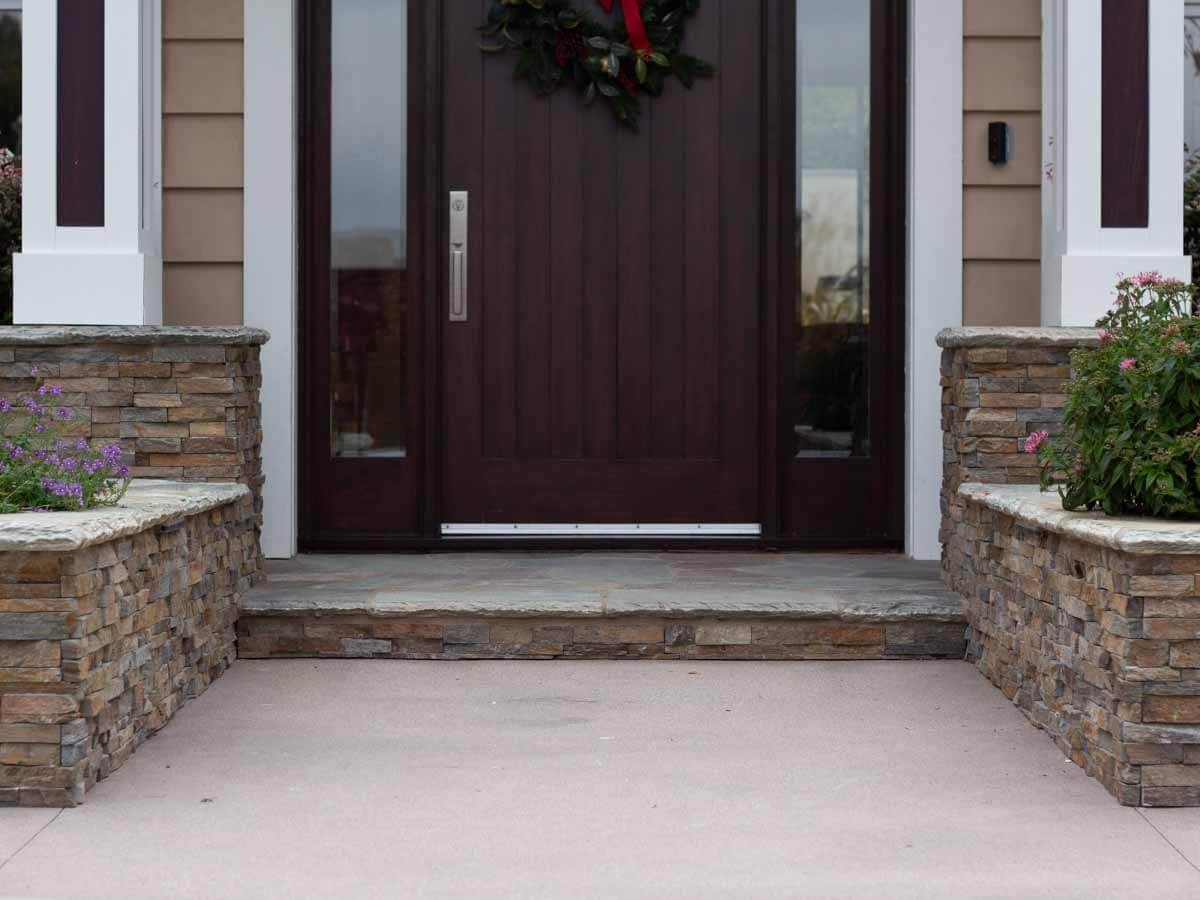 Front porch with stacked stone knee walls flanking a smooth concrete landing