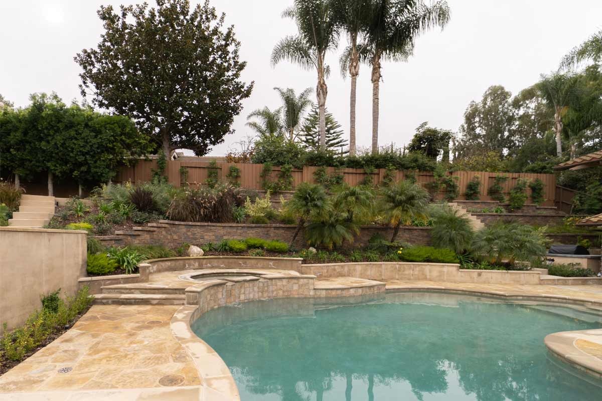 Dry-stacked ledger stone raised wall with travertine coping beside a pool