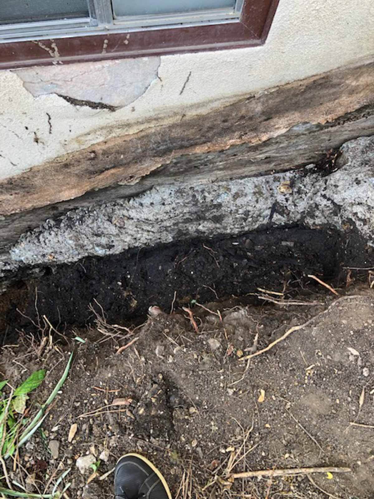 Foundation excavated to expose rotted wood and failed waterproofing before repair