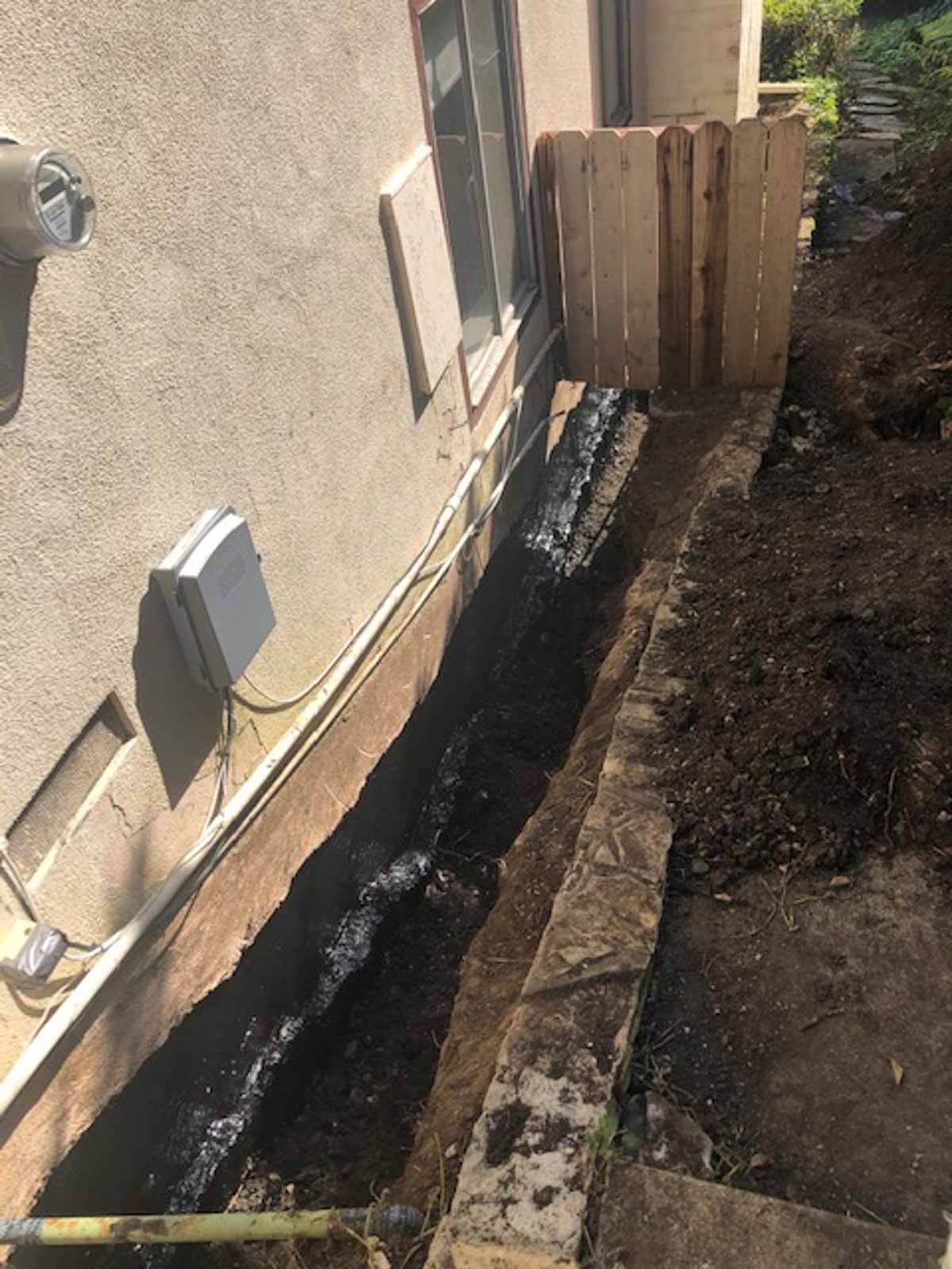 Waterproofing membrane running along a stucco wall in an open trench